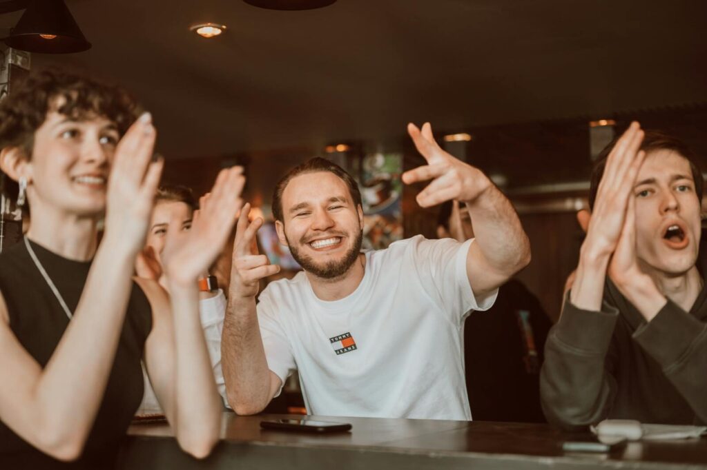 A group of adults applauding and cheering indoors with joyful expressions.