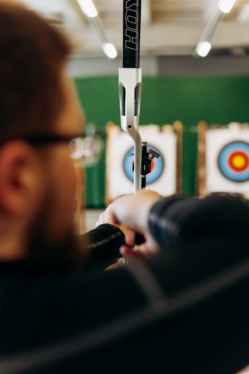 Archer aiming at targets indoors, showcasing concentration and skill.