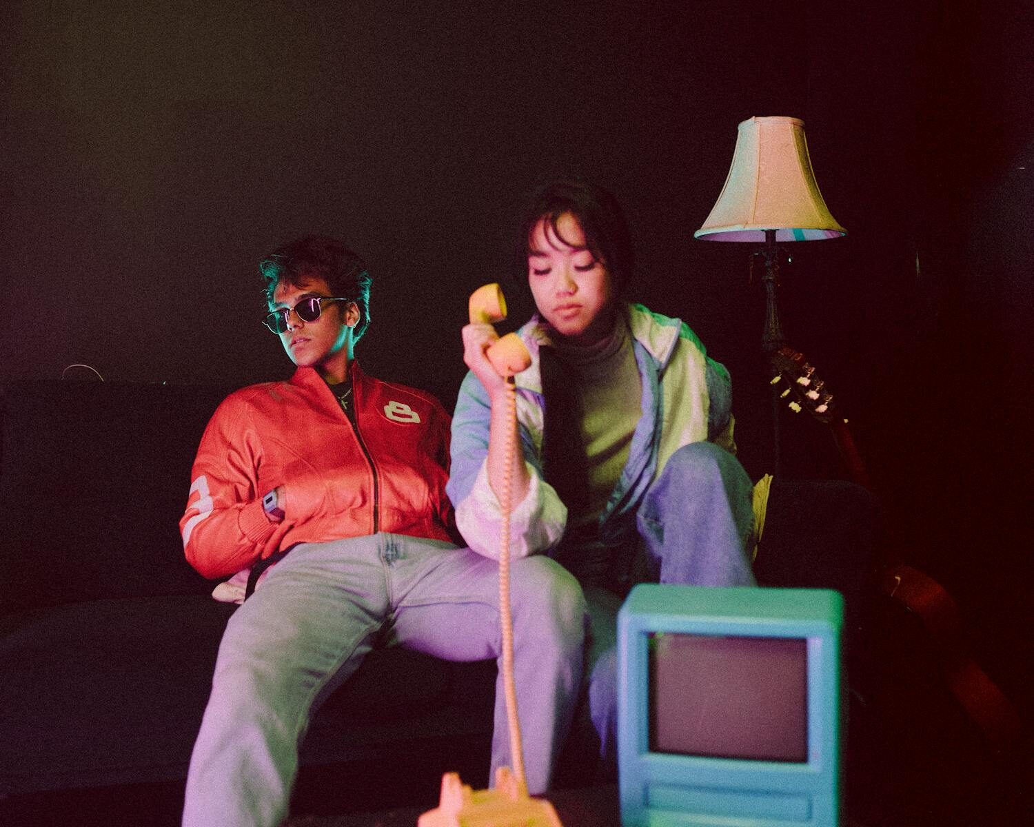 Fashionable couple in retro setting with vintage phone and television. Stylish and trendy vibe.